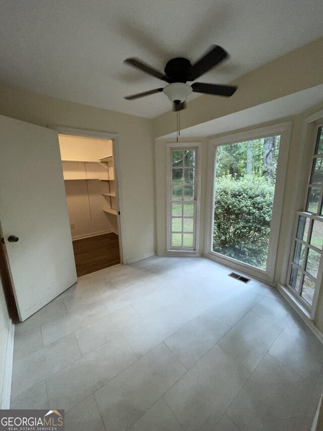 unfurnished bedroom with light tile patterned flooring, ceiling fan, a closet, and a spacious closet