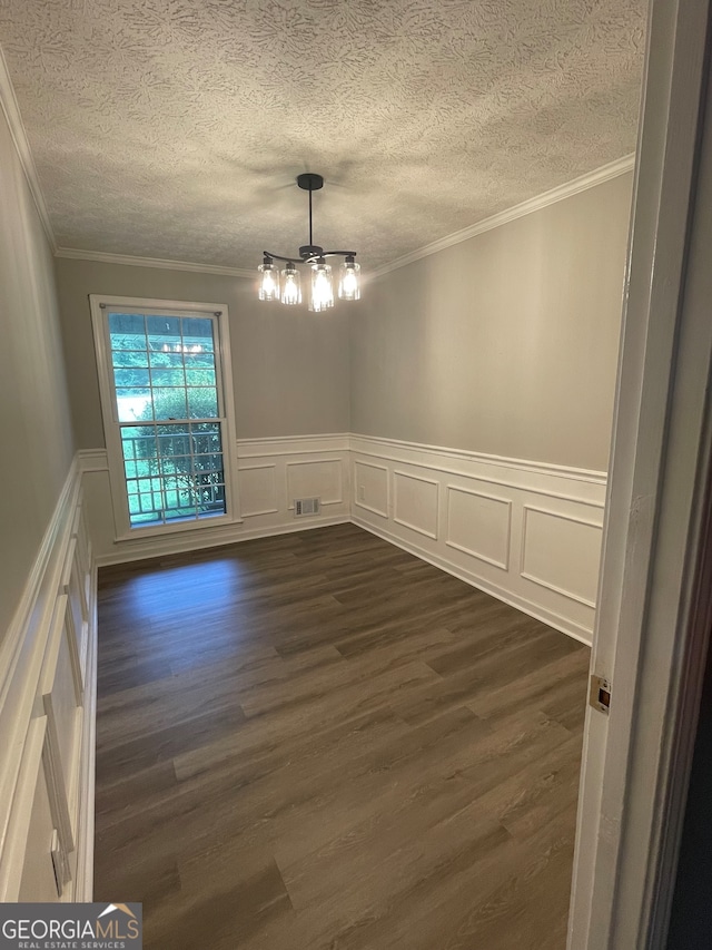 empty room featuring crown molding, a textured ceiling, dark hardwood / wood-style flooring, and a notable chandelier