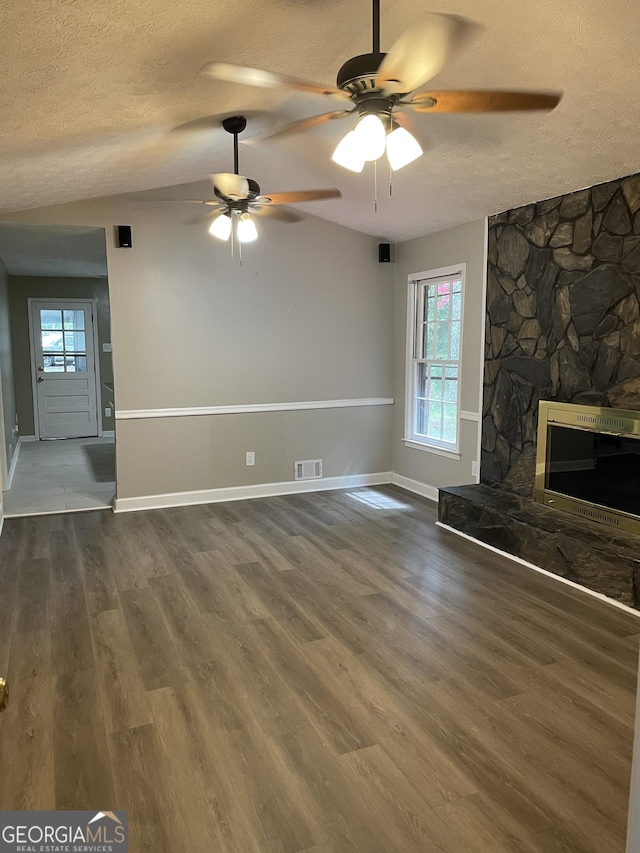 unfurnished living room with a stone fireplace, wood-type flooring, and a healthy amount of sunlight