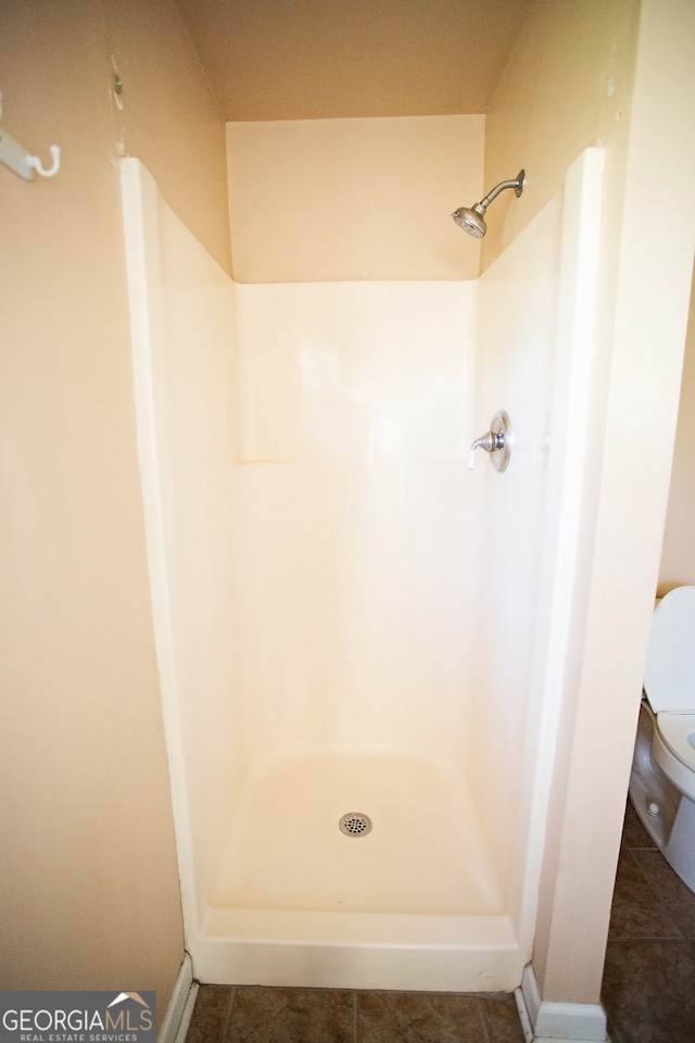 bathroom featuring tile patterned floors, toilet, and walk in shower