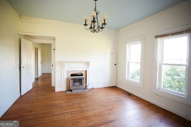 unfurnished living room with hardwood / wood-style floors, a chandelier, and heating unit