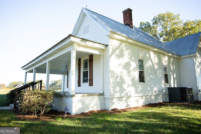 view of side of home with central AC, a lawn, and a porch