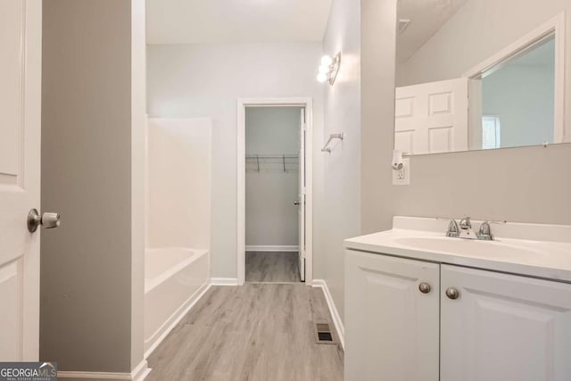 full bath featuring baseboards, vanity, wood finished floors, and visible vents