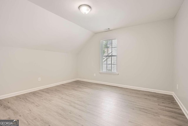 additional living space featuring light hardwood / wood-style floors and vaulted ceiling