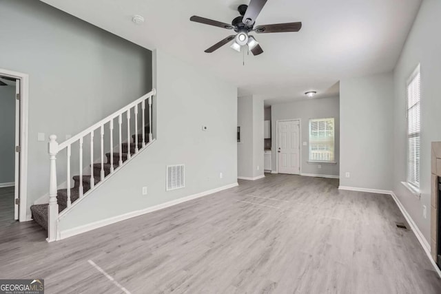 unfurnished living room featuring plenty of natural light, wood finished floors, visible vents, and ceiling fan