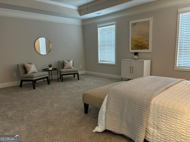 carpeted bedroom featuring ornamental molding and a tray ceiling