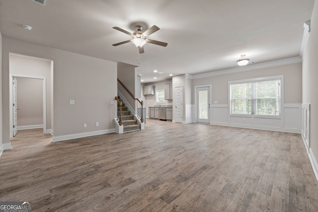 unfurnished living room featuring crown molding, wood-type flooring, ceiling fan, and plenty of natural light