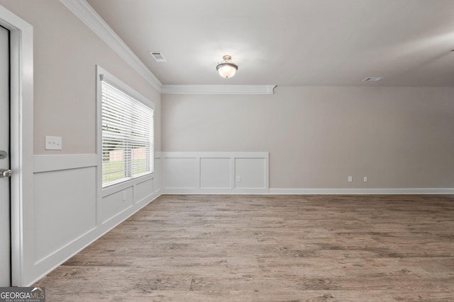 spare room with ornamental molding and light hardwood / wood-style floors