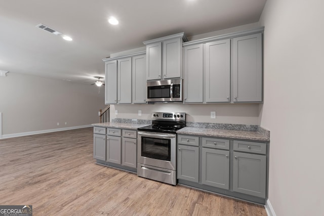 kitchen featuring stainless steel appliances, gray cabinetry, and light hardwood / wood-style floors