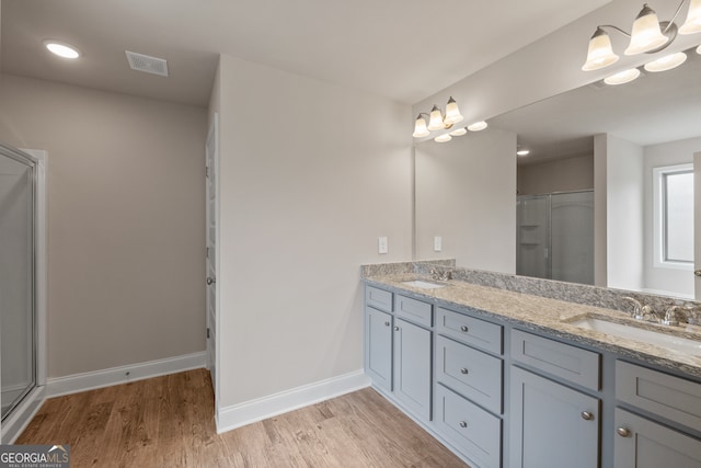 bathroom featuring an enclosed shower, wood-type flooring, a notable chandelier, and vanity