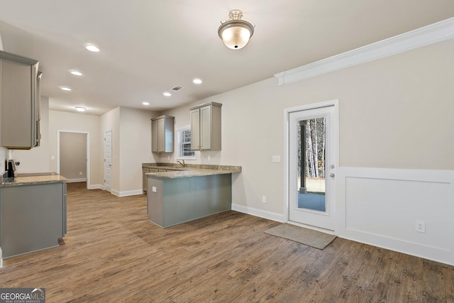 kitchen featuring sink, crown molding, wood-type flooring, gray cabinets, and kitchen peninsula