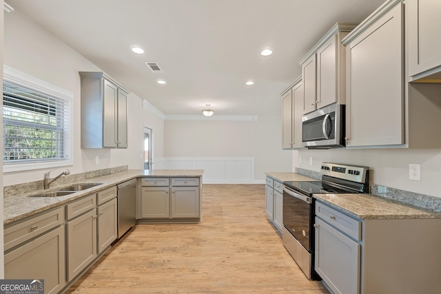 kitchen with sink, gray cabinets, stainless steel appliances, light hardwood / wood-style floors, and kitchen peninsula