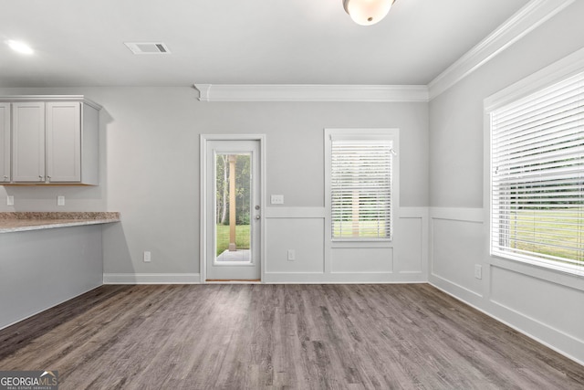 interior space featuring a healthy amount of sunlight, dark wood-type flooring, and ornamental molding