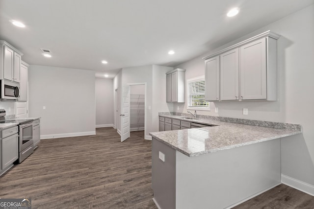 kitchen featuring dark wood-type flooring, sink, light stone counters, appliances with stainless steel finishes, and kitchen peninsula