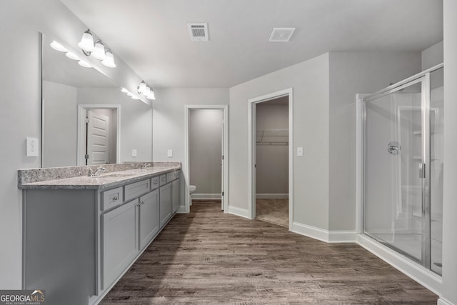 bathroom featuring toilet, vanity, a shower with door, and hardwood / wood-style floors