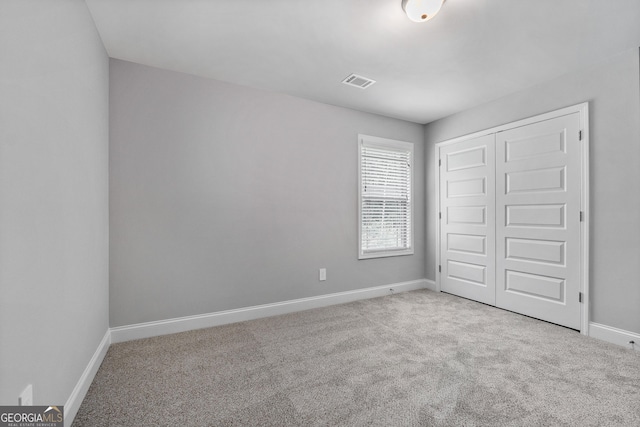 unfurnished bedroom with light carpet and a closet