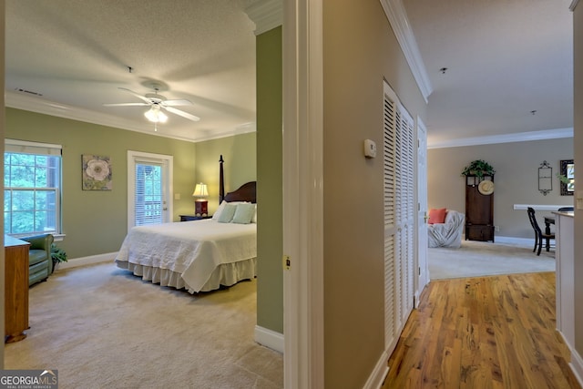 carpeted bedroom with ceiling fan, a closet, and ornamental molding