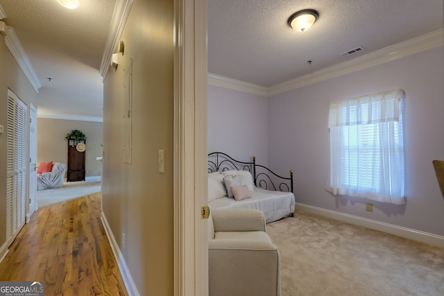 hall with ornamental molding, light carpet, and a textured ceiling