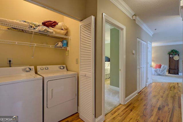 washroom with ornamental molding, light carpet, a textured ceiling, and independent washer and dryer