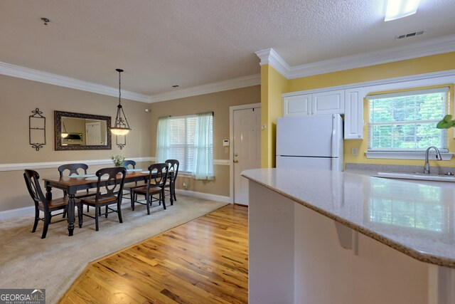 kitchen featuring white cabinets, sink, white fridge, crown molding, and light carpet