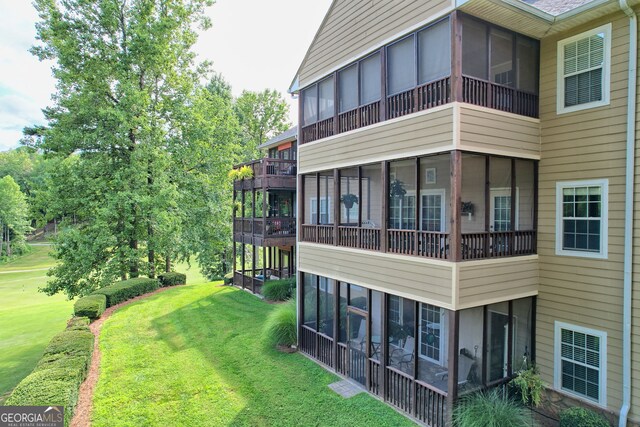 exterior space with a balcony, a sunroom, and a yard