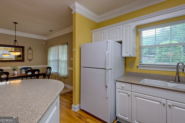 kitchen with white cabinetry, white refrigerator, ornamental molding, sink, and light hardwood / wood-style flooring