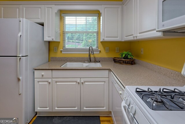 kitchen with sink, white cabinetry, hardwood / wood-style flooring, and white appliances