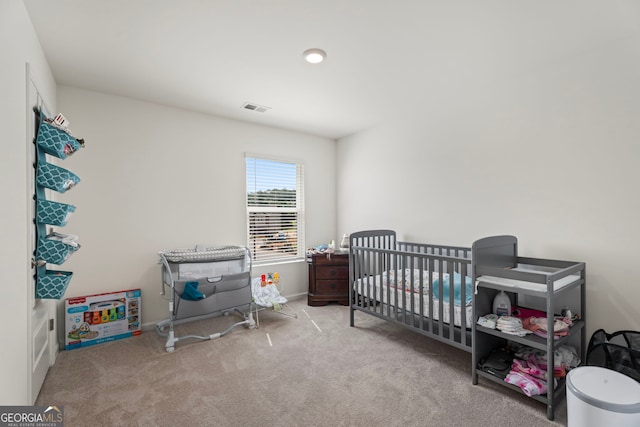 carpeted bedroom featuring a nursery area