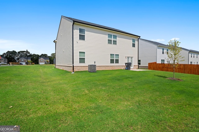 rear view of house with cooling unit and a lawn