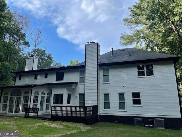 rear view of house with central AC unit, a deck, and a lawn