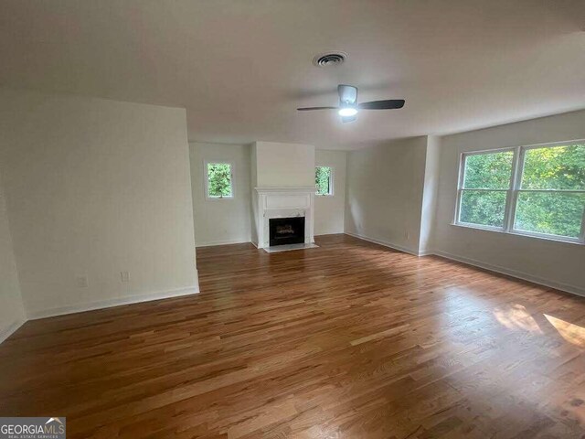 unfurnished living room featuring plenty of natural light, hardwood / wood-style flooring, and ceiling fan