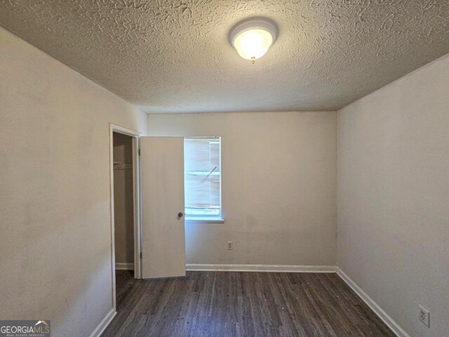 empty room featuring a textured ceiling and dark hardwood / wood-style floors