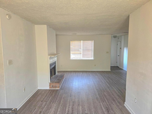 unfurnished living room with dark wood-type flooring, a fireplace, and a textured ceiling