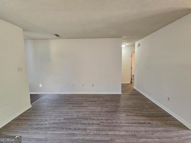 unfurnished room with a textured ceiling and hardwood / wood-style floors