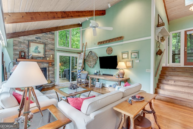 living room with wooden ceiling, high vaulted ceiling, a stone fireplace, hardwood / wood-style flooring, and ceiling fan