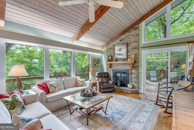 sunroom / solarium featuring vaulted ceiling with beams, ceiling fan, wood ceiling, and a fireplace