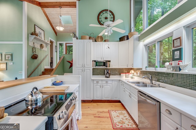 kitchen with hanging light fixtures, tasteful backsplash, vaulted ceiling with beams, white cabinets, and appliances with stainless steel finishes