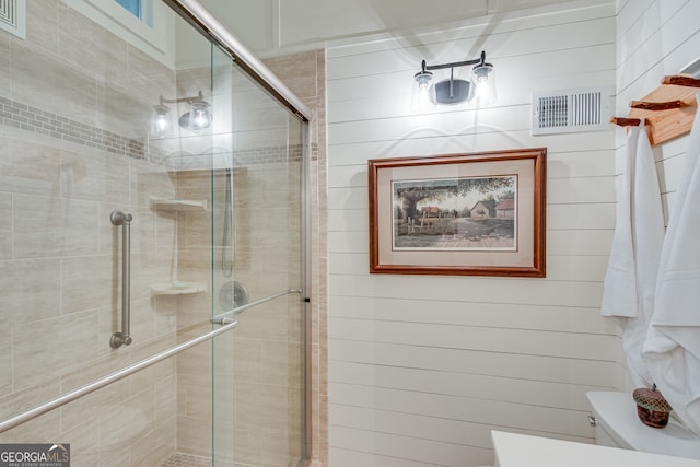 bathroom with a shower with door and toilet