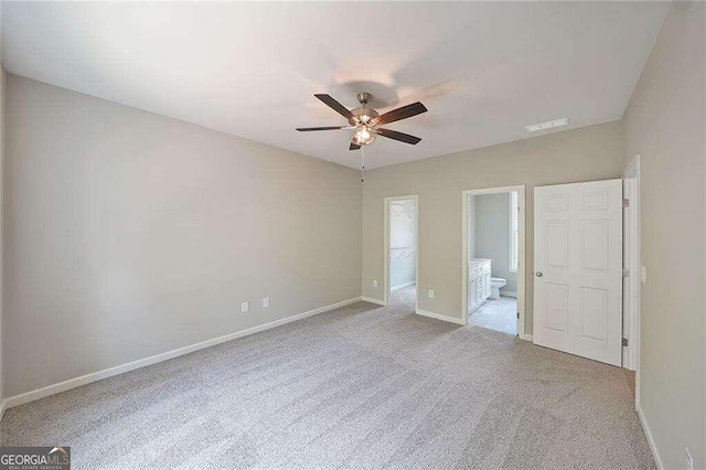 unfurnished bedroom featuring a spacious closet, light colored carpet, a closet, and ceiling fan