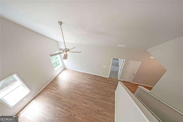 interior space with wood-type flooring, vaulted ceiling with skylight, and ceiling fan