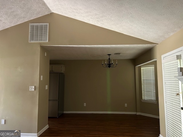 unfurnished room featuring vaulted ceiling, a notable chandelier, a textured ceiling, and dark hardwood / wood-style flooring