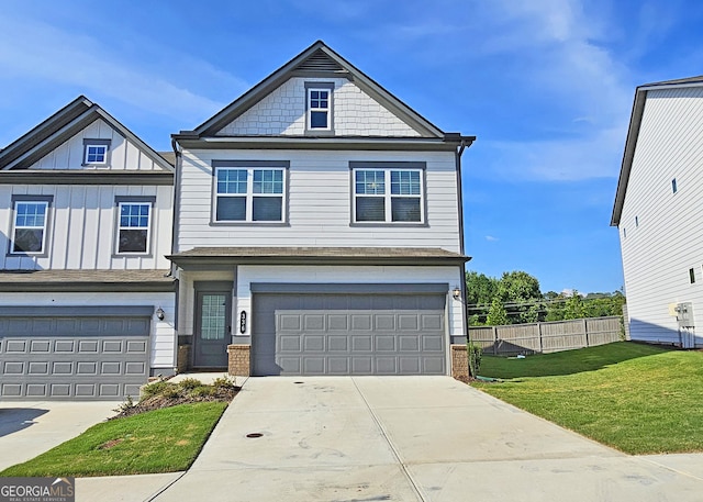 view of front of home featuring an attached garage, board and batten siding, a front yard, fence, and driveway