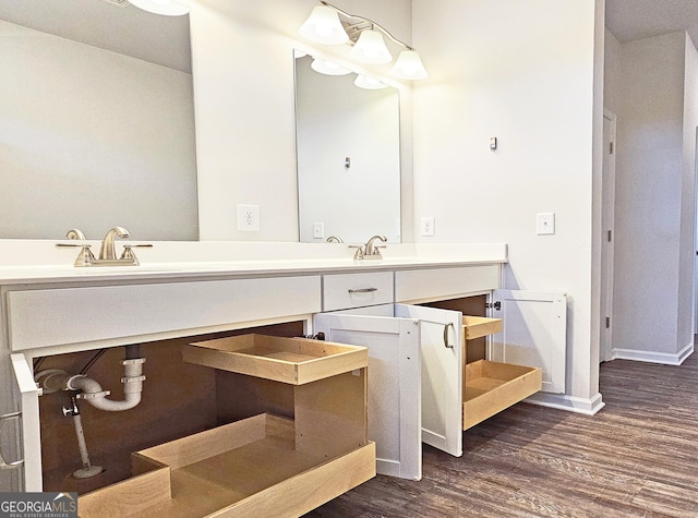 bathroom with double vanity, a sink, baseboards, and wood finished floors