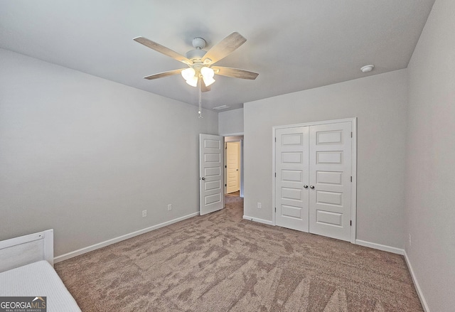 unfurnished bedroom featuring a ceiling fan, a closet, baseboards, and carpet flooring