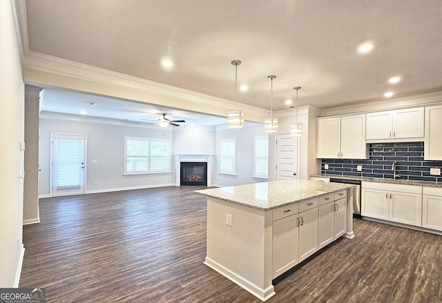 kitchen with dark wood finished floors, decorative backsplash, a kitchen island, crown molding, and stainless steel dishwasher