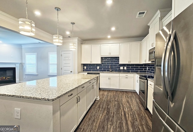 kitchen featuring visible vents, appliances with stainless steel finishes, white cabinetry, a sink, and a kitchen island