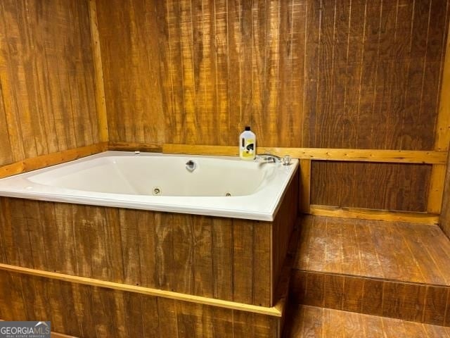 bathroom featuring a tub and wooden walls