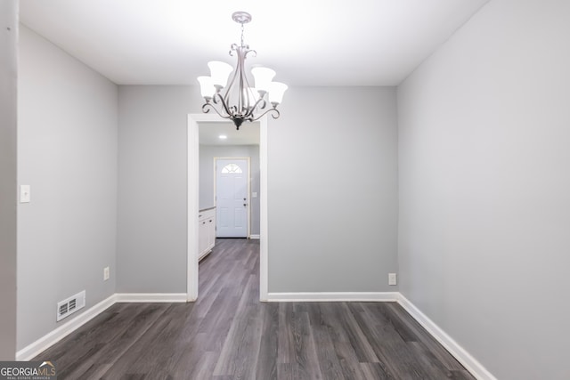 unfurnished dining area featuring dark wood-type flooring and a notable chandelier