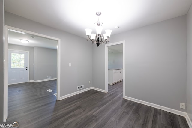 unfurnished room with dark wood-type flooring and an inviting chandelier