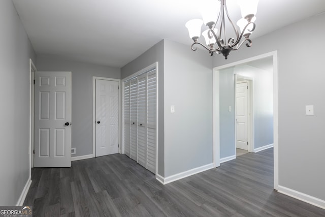 corridor with dark hardwood / wood-style floors and a chandelier